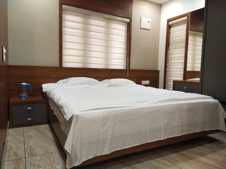 A double bed with white linen beneath a window with striped blinds
